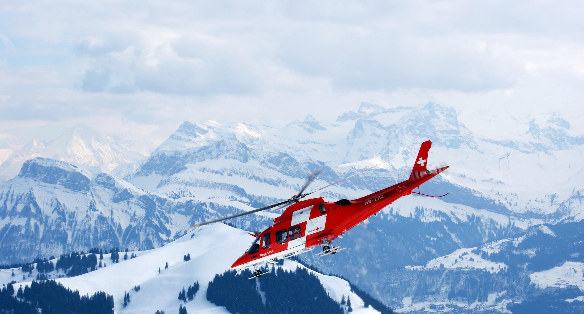 photo of flight of red and white rescue helicopter during snow daytime